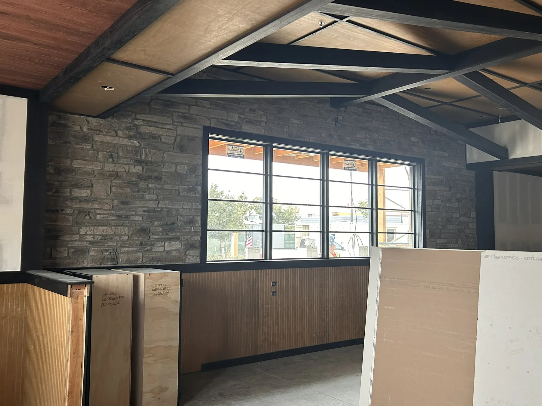 Stacked stone accent wall and vaulted wood ceiling in an unfinished great room