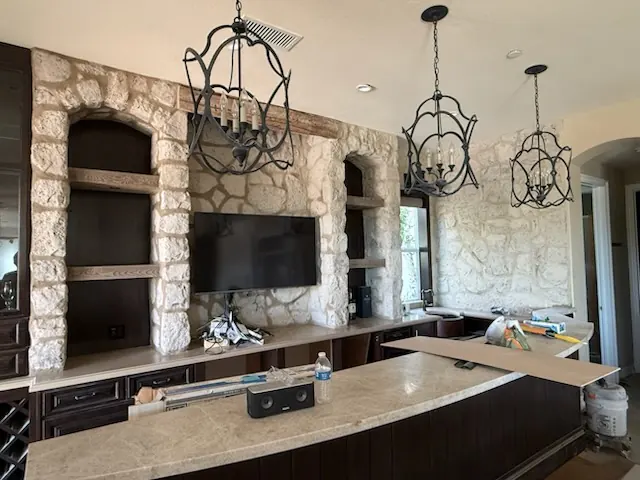 Stacked stone fireplace wall with built-in shelving flanking a mounted TV