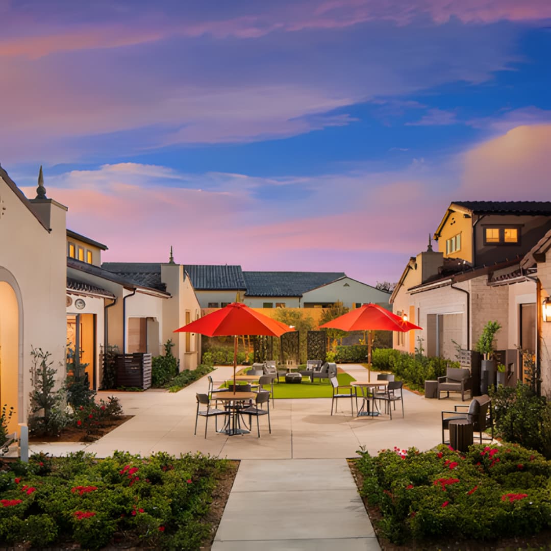 Outdoor courtyard with red umbrellas and seating at sunset
